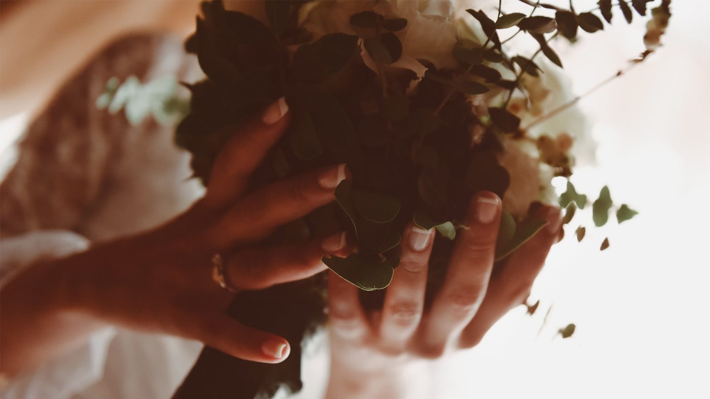Wedding rings held over a bouquet